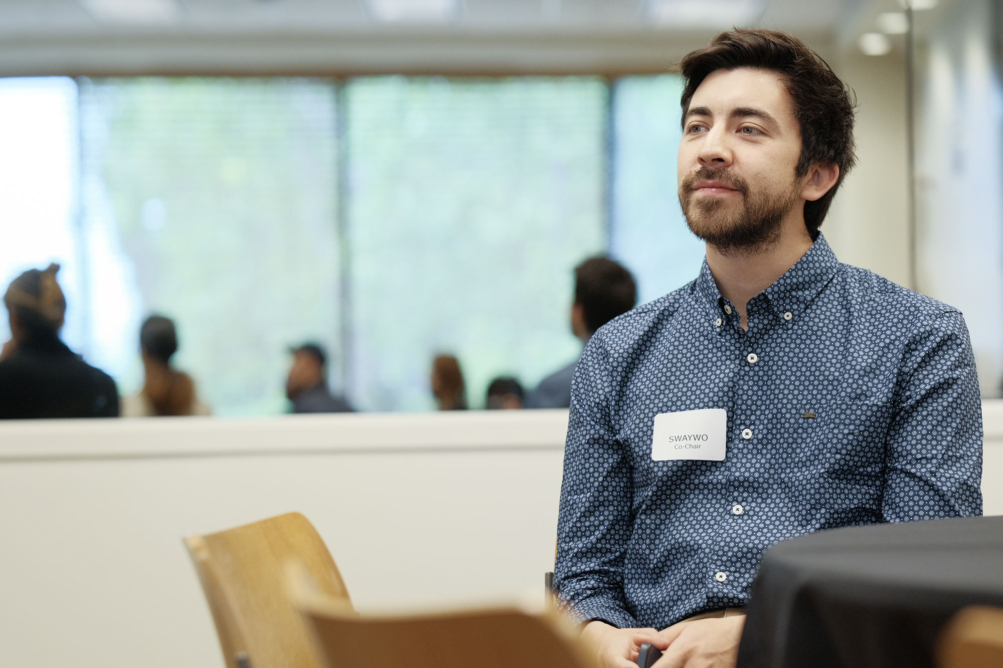 Male student sitting at a table listening to a presentation