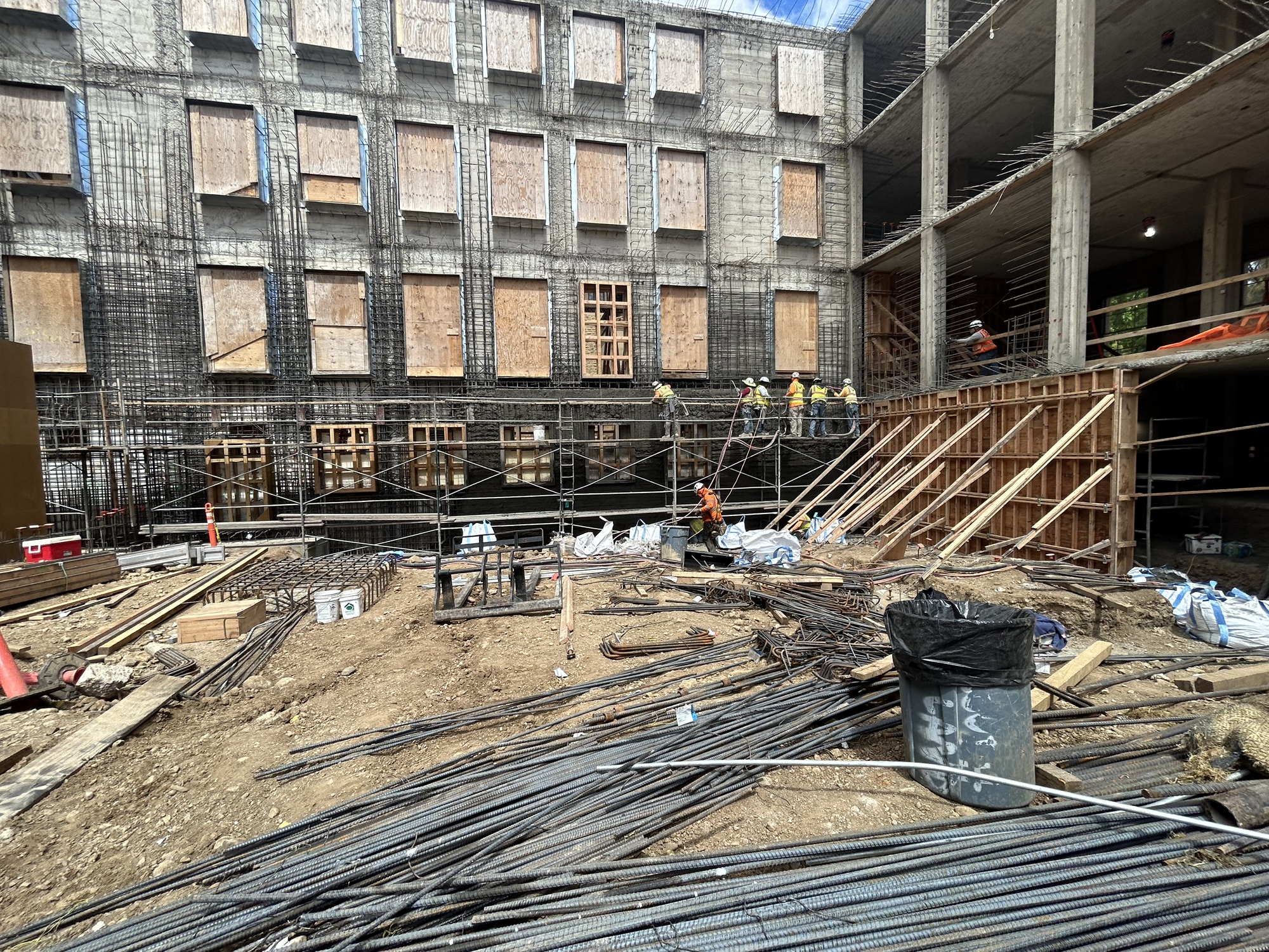 Image of workers on scaffolding working on structural framing, with four levels of a building visible