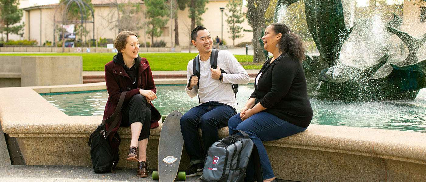 Photo of a group of students laughing in front of a water fountain.