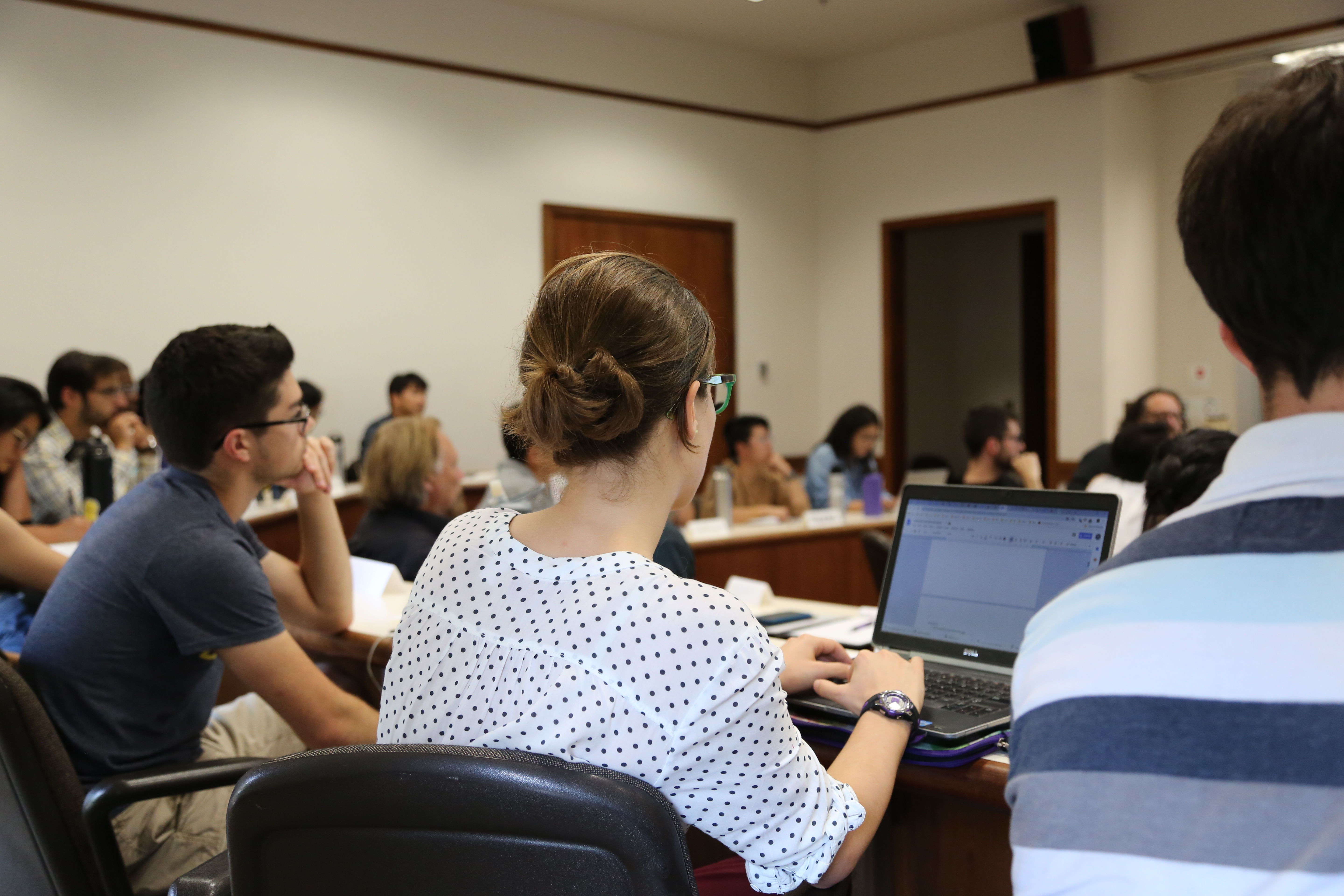 Students at an auditorium listening and working on computer