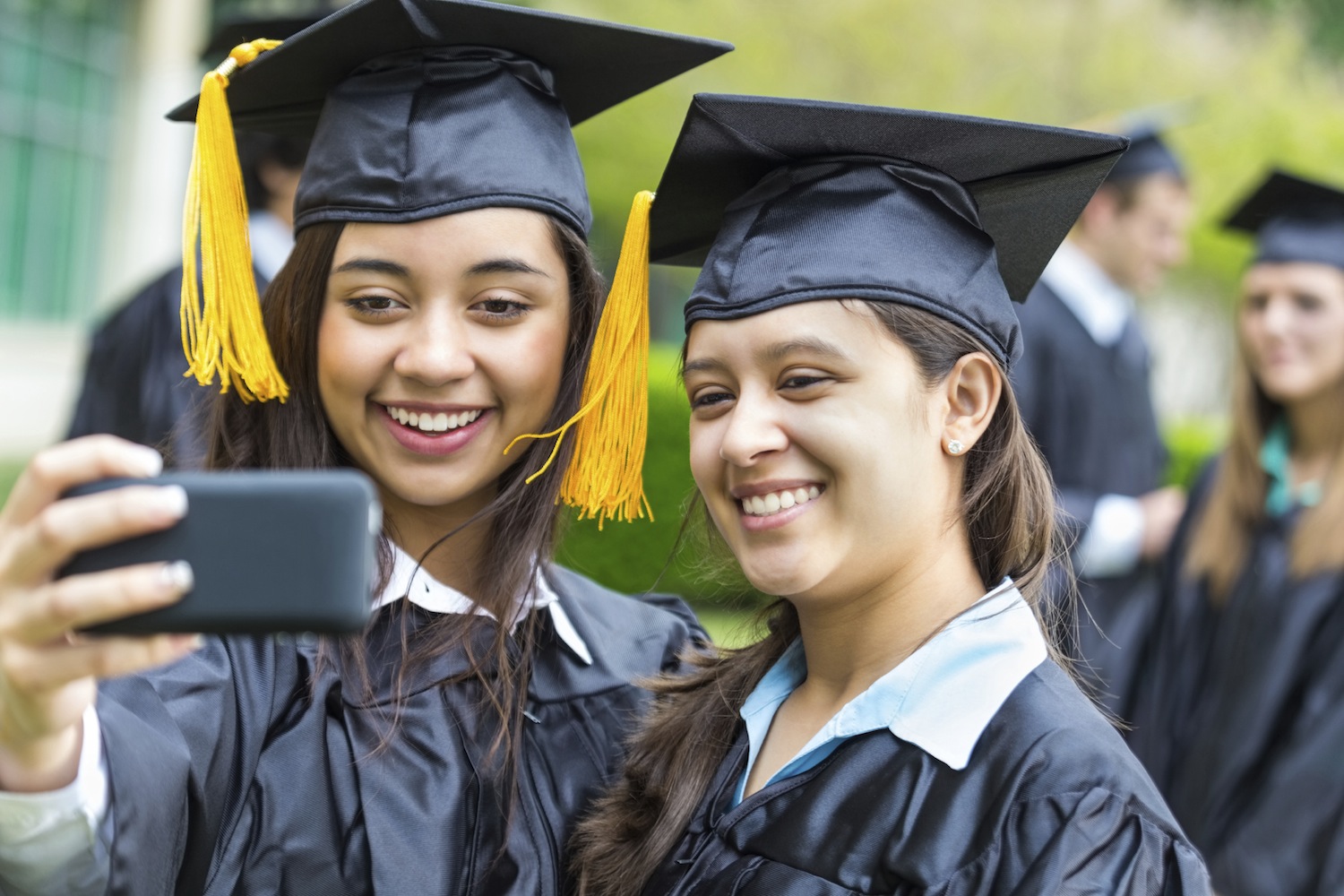 Two female students in their graduation gowns taking a self-portrait