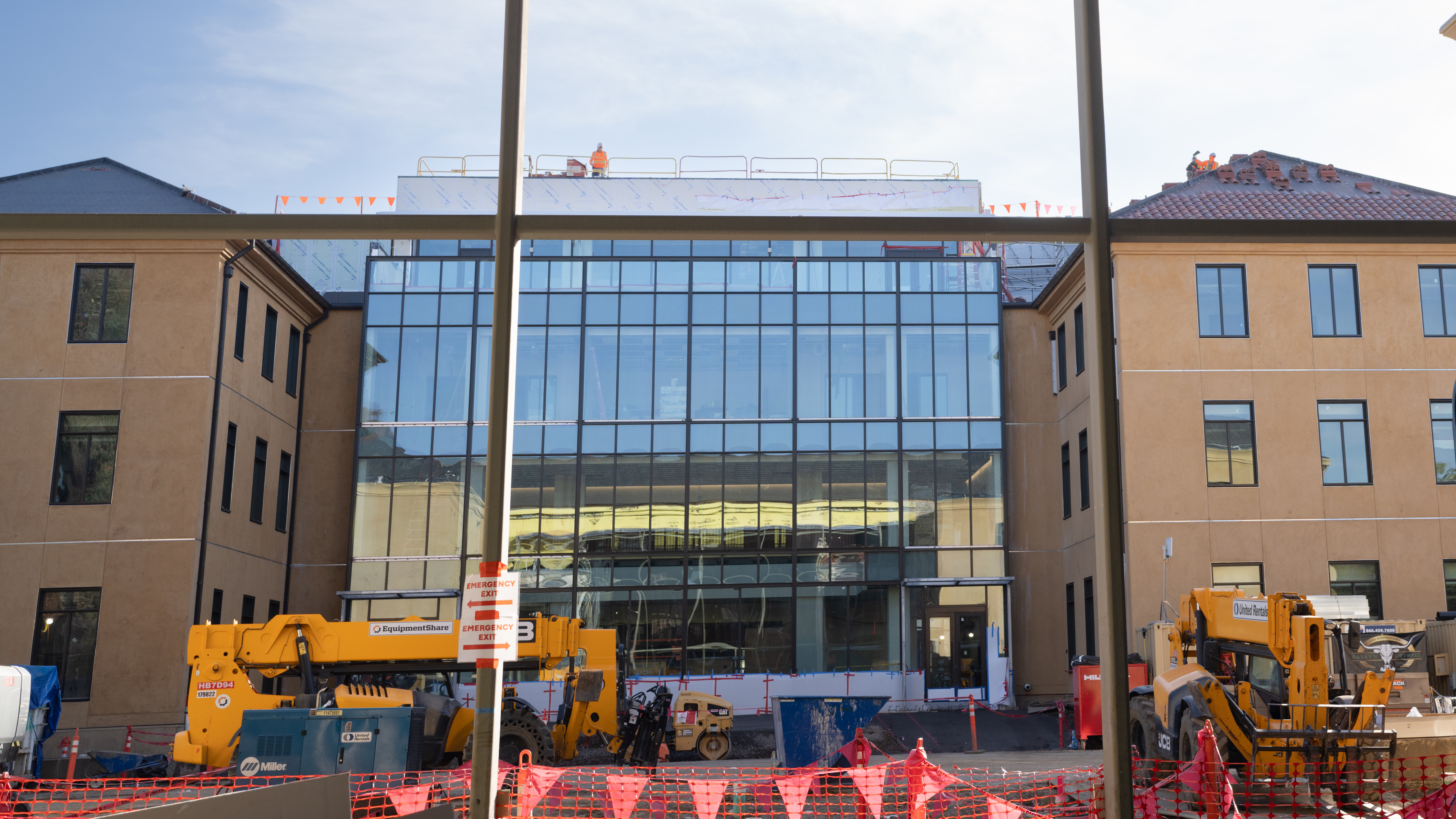 Photo of the south building under construction, with the new glass wall complete and construction workers on the roof