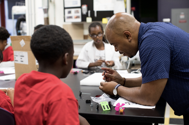 Male teacher helping a student troubleshoot a project.