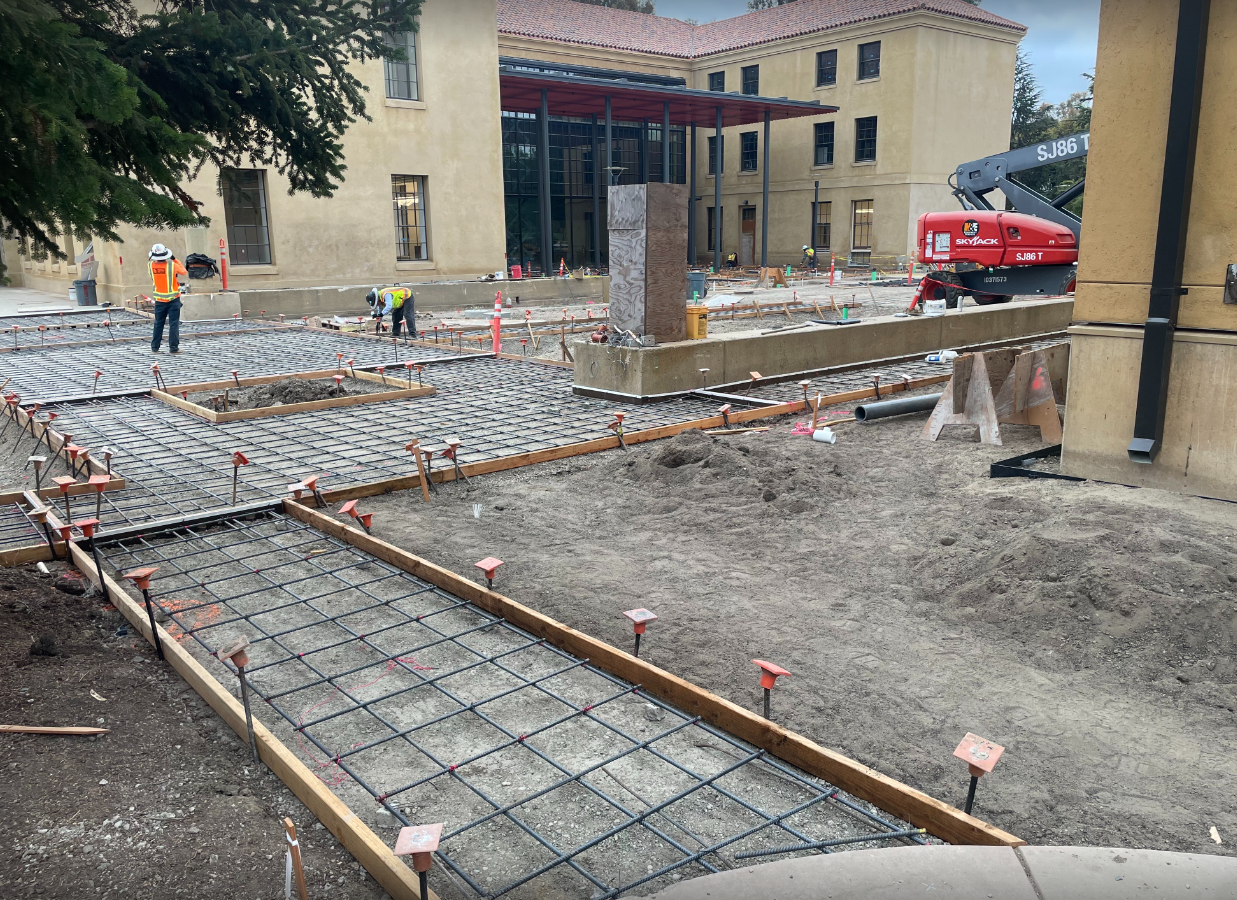 workers laying rebar for pathways and the courtyard, with the ANKO Building in the background