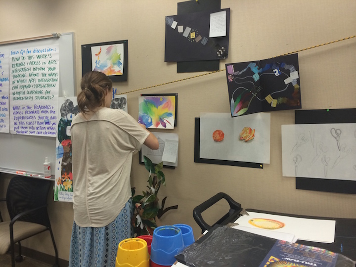 Student placing her work on wall