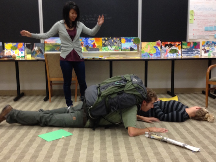 Two students lying on the group with one student surprised