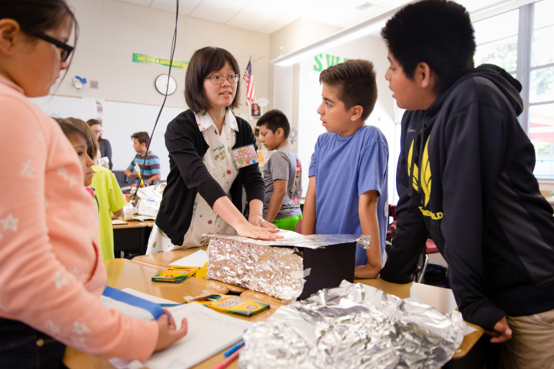 Female teacher working with a table of students.