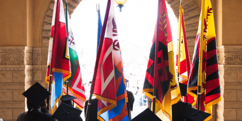 Image in color that shows graduates holding the flags of Stanford's seven different graduate and professional schools