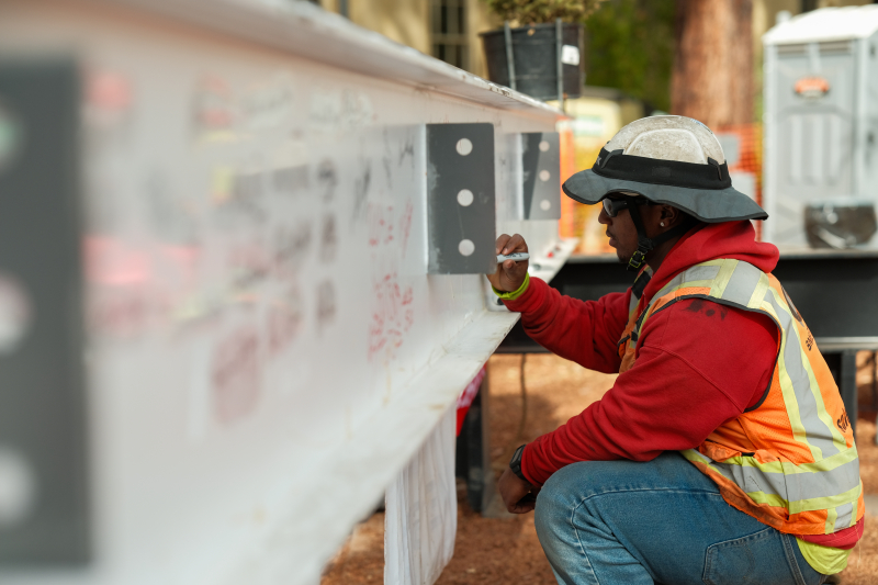 A construction worker signs his name to the final beam of the new building. (Photo: Ryan Zhang)
