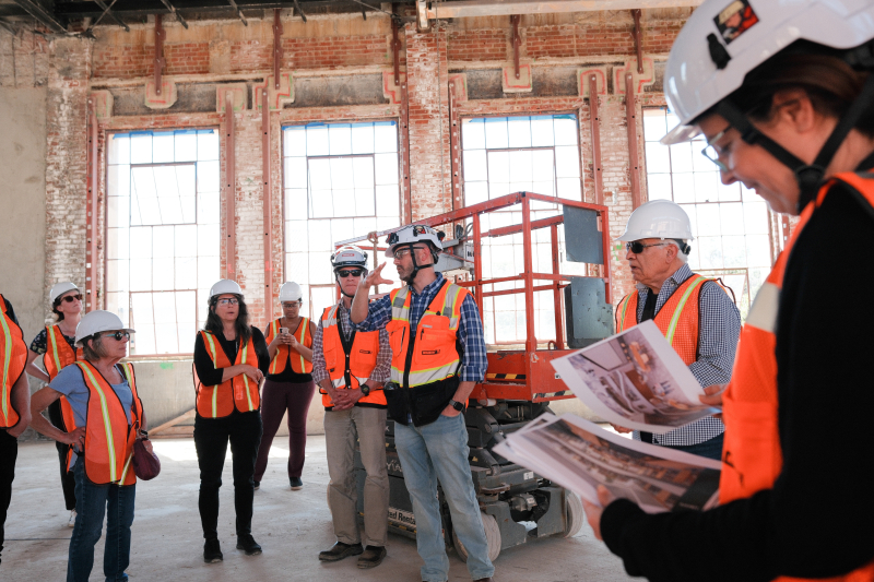 Michael Mithen (center left) and Jeff Ivey (center right) lead a tour for faculty and staff on May 9, 2024. The windows and bricks in the background are original to the 1930s building. (Photo: Ryan Zhang)
