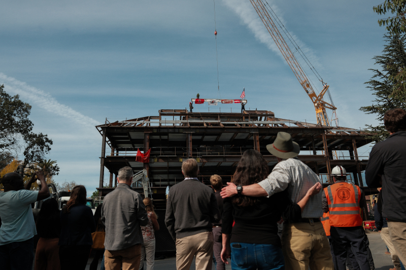 Onlookers watch as workers lower the final steel beam onto the top of the new south building, October 31, 2023 (photo: Ryan Zhang)