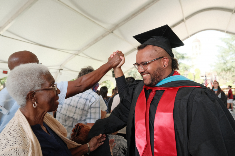 A Stanford GSE graduate student greeting friends and family at the GSE Diploma Ceremony.