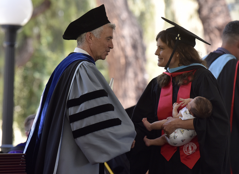 A Stanford Teacher Education Program graduate receives her diploma from Dean Dan Schwartz with the newest member of her family. (Photo: Charles Russo)