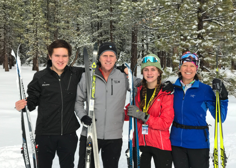 A family posing for a picture with ski on a snowy background 