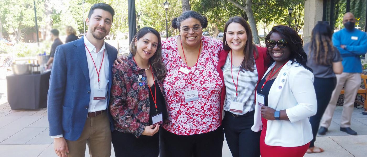 Photo of Dean Ann Charity Hudley with four students on either side posing for the picture during an event