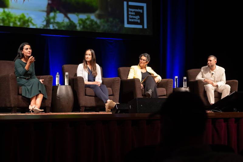 Photo of a stage with a speaker and moderators