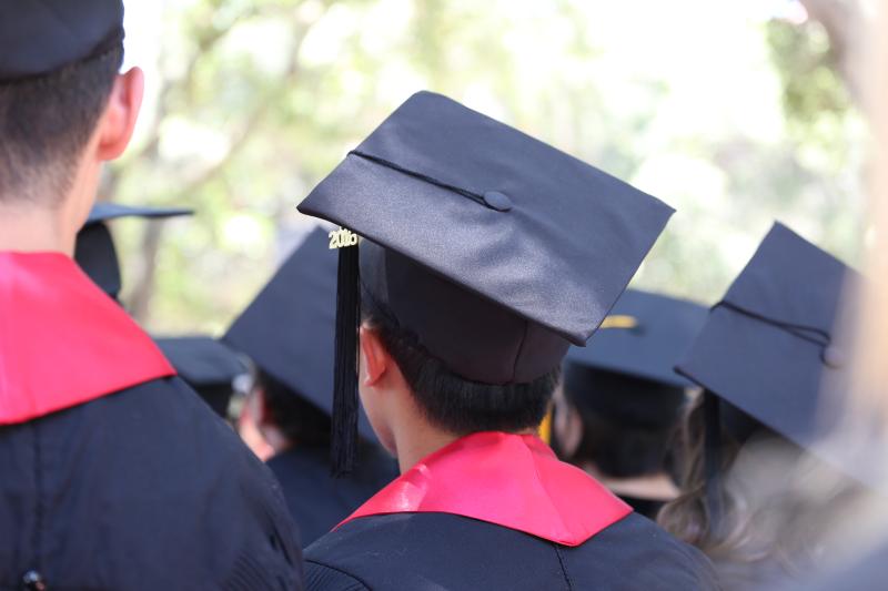 The back of graduating students in their caps and gowns.