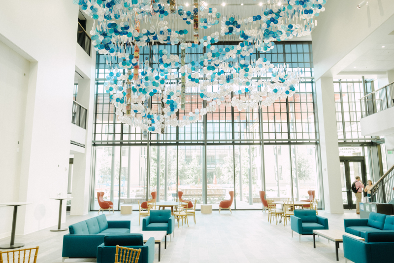 A photo showing the art installation in a light, airy three-story lobby or forum, looking toward the windows