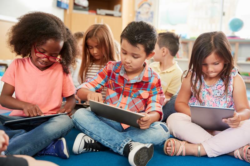 Group of early elementary age students working on tablets