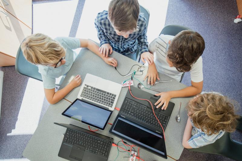 Overhead photo of 4 students working on two laptops.