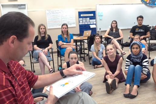 STEP students siting on the floor while faculty is reading them a kids book