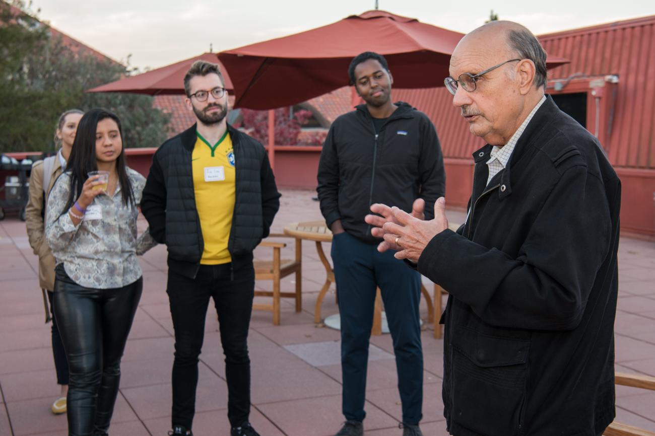 Photo of Mike Kirst talking with students at a reception for the MA/MBA program