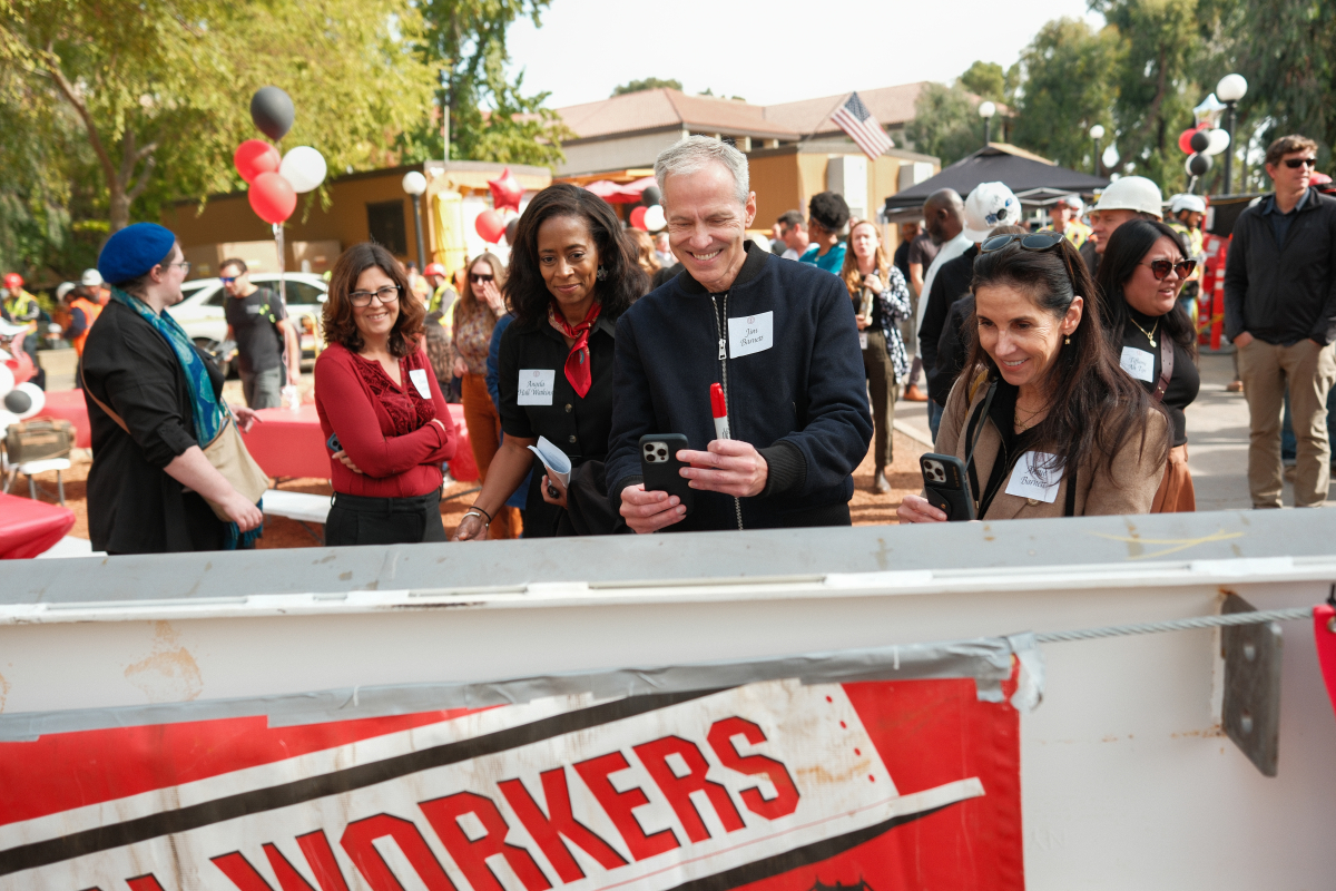 Construction workers and Stanford community members take turns signing the building's final beam. (Photo: Ryan Zhang)