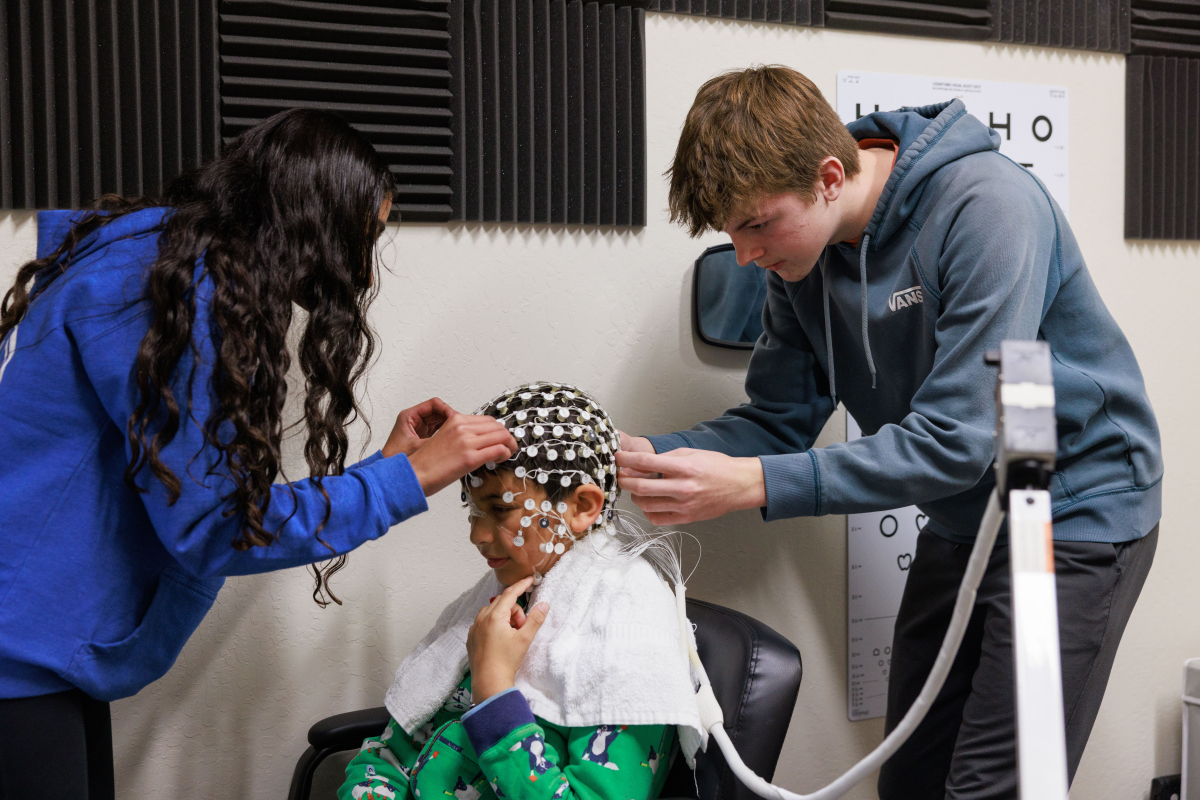 Middle school students affix an EEG cap to a fellow student for a study