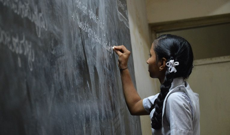 Photo of young woman writing on a chalkboard