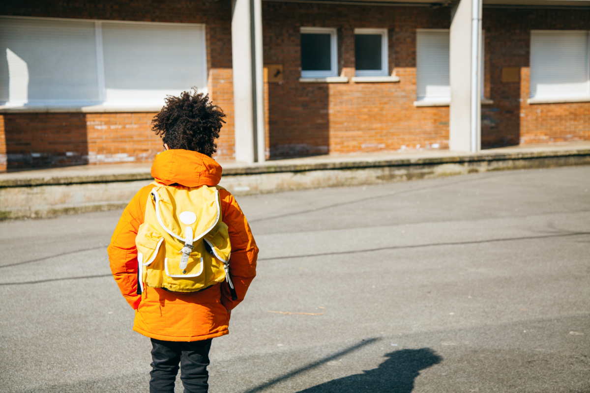 Photo of young Black student approaching a deserted school building
