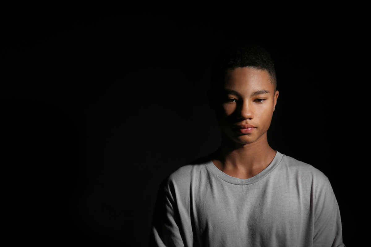 Photo of a Black teenager against a dark background