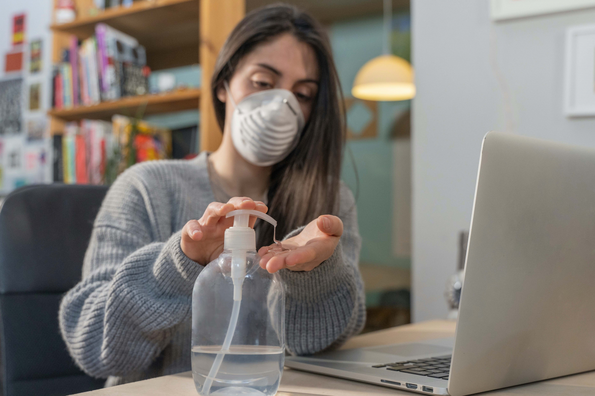 Photo of woman watching video, wearing mask and using hand sanitizer