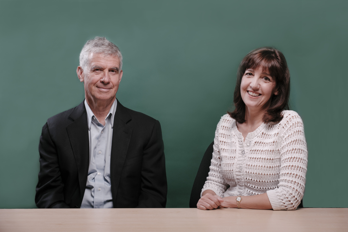 Photo of GSE Dean Dan Schwartz and Senior Lecturer Denise Pope sitting at a table, smiling at the camera