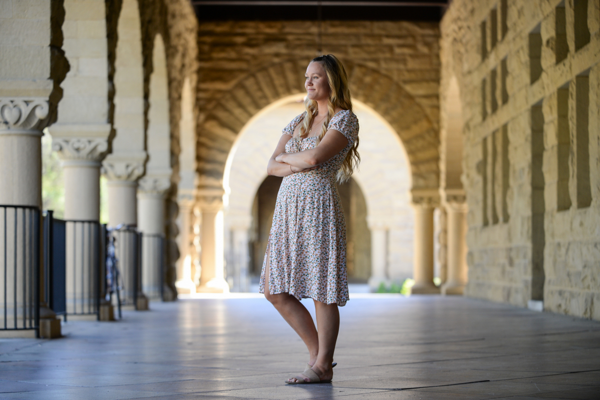 Photo of Lucy Caffrey-Maffei standing in one of the arcades of Stanford's Main Quad