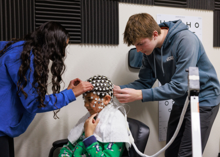 Middle school students affix an EEG cap to a fellow student for a study