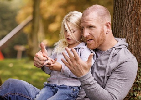 Child counting on fingers outside with her father