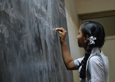 Photo of young woman writing on a chalkboard