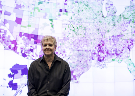 Photo of Sean Reardon in front of U.S. map showing school achievement data