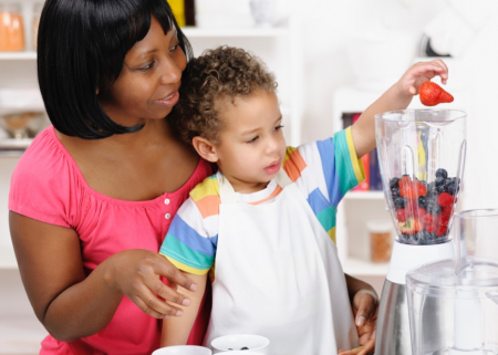 Toddler helping his mother preparing a smoothie