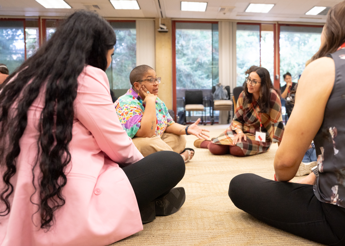 Students sitting in a circle on the floor, in discussion