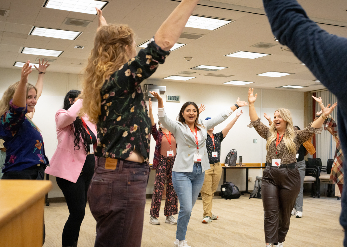 Students participating in at improv session, raising their hands above their heads