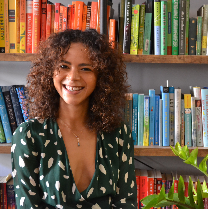 Kia Turner smiling in front of beautifully colorful books
