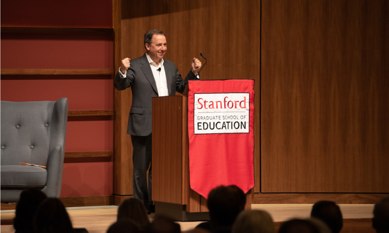 Ron Suskind speaking behind a podium with Stanford GSE logo