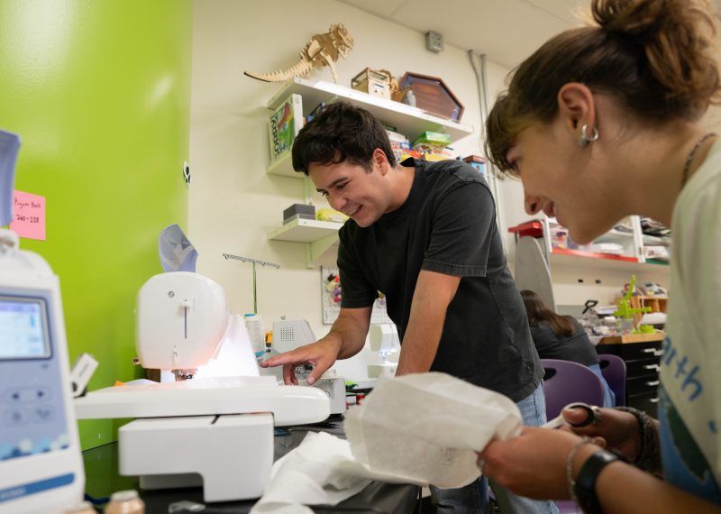 Two students using a piece of equipment in the GSE Makery.