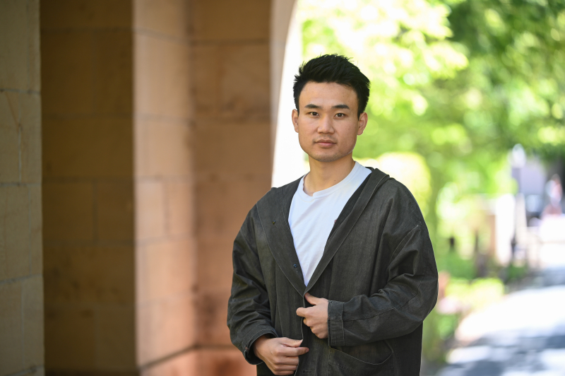 Photo of Haroan "Elvis" Wu standing under a Stanford arch