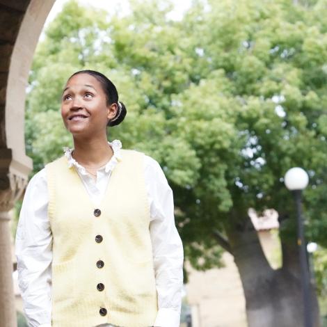 Photo of Camille Fabo, standing in one of the Stanford archways, smiling and looking up