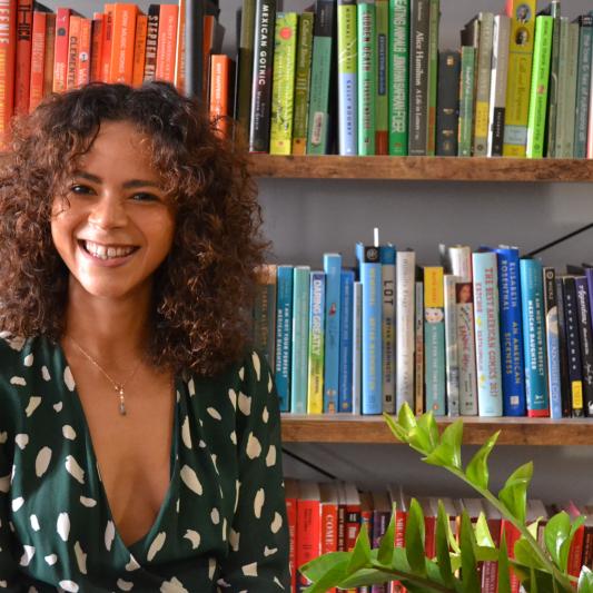 Kia Turner smiling in front of beautifully colorful books