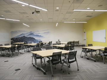 Image of a big room with table, chairs and whiteboards