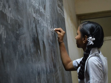 Photo of young woman writing on a chalkboard