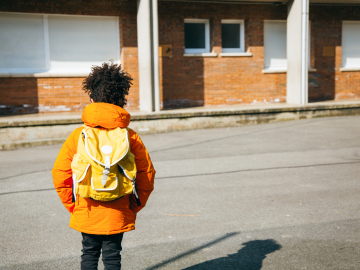 Photo of young Black student approaching a deserted school building